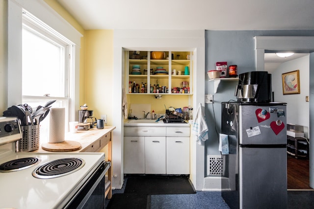 kitchen with a sink, white cabinets, electric stove, light countertops, and freestanding refrigerator