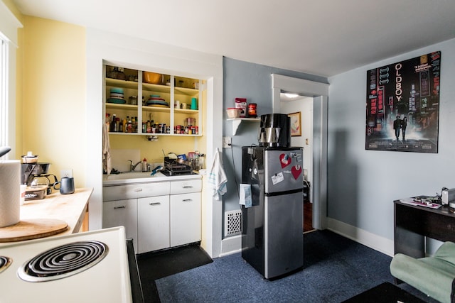 kitchen featuring a sink, white cabinetry, baseboards, light countertops, and freestanding refrigerator