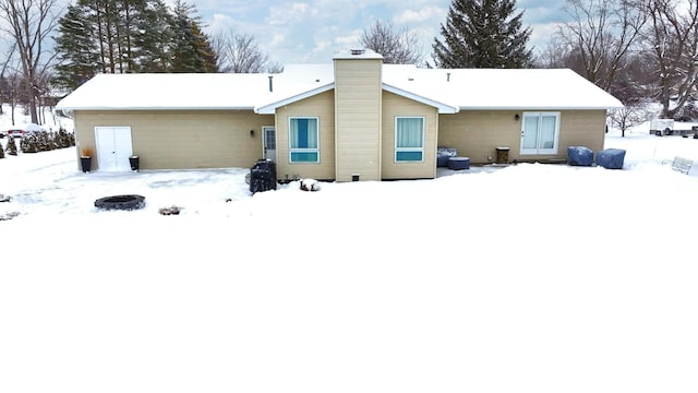 snow covered house featuring a chimney and a fire pit