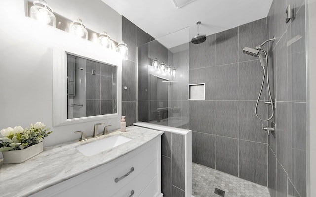 full bathroom featuring tiled shower and vanity