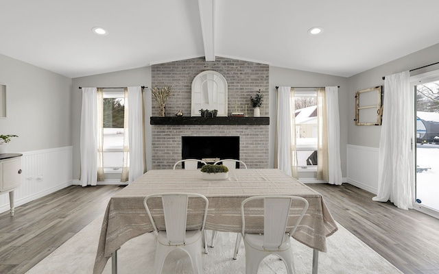 dining area featuring a wainscoted wall, lofted ceiling with beams, and a healthy amount of sunlight