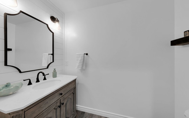 bathroom with wood finished floors, vanity, and baseboards