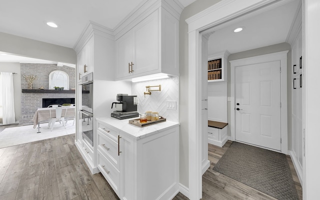 kitchen with light countertops, light wood finished floors, white cabinetry, and decorative backsplash