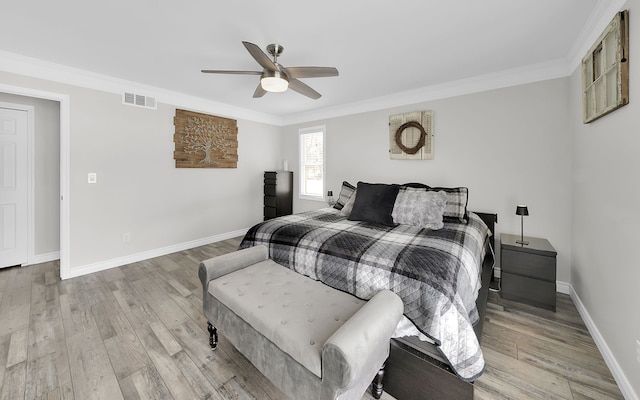 bedroom featuring light wood finished floors, baseboards, visible vents, and ornamental molding