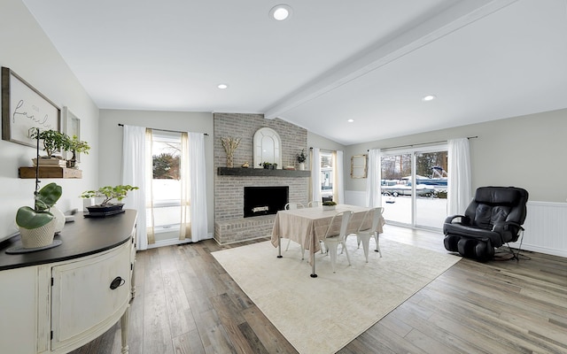 living room featuring lofted ceiling with beams, a fireplace, wainscoting, and wood finished floors