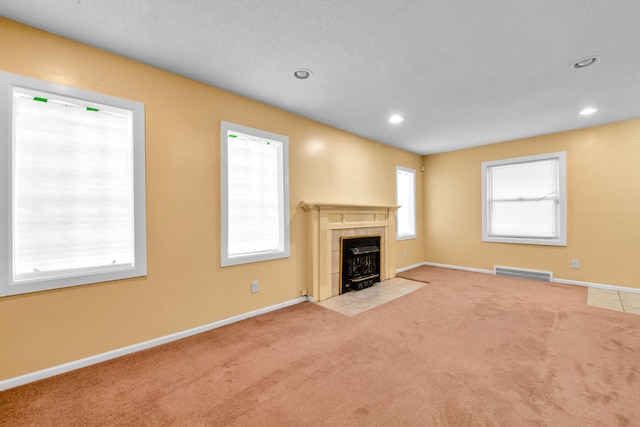 unfurnished living room with a tile fireplace and light colored carpet