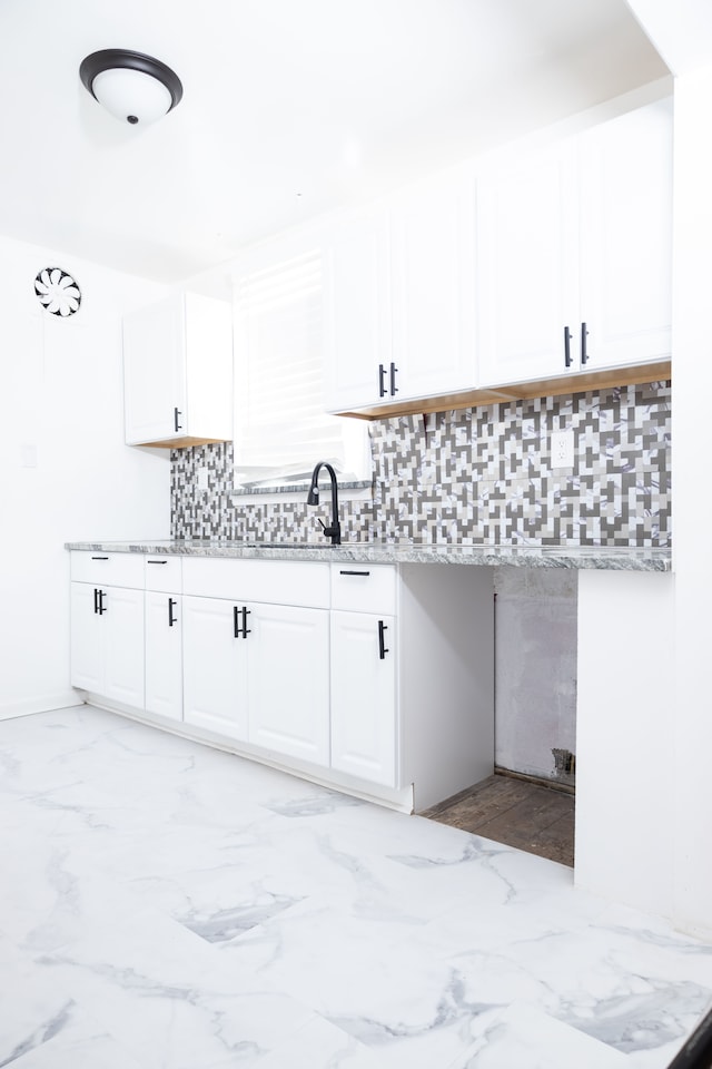 kitchen with decorative backsplash, light stone countertops, marble finish floor, and white cabinets