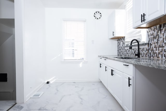 kitchen with light stone counters, baseboards, a sink, decorative backsplash, and marble finish floor