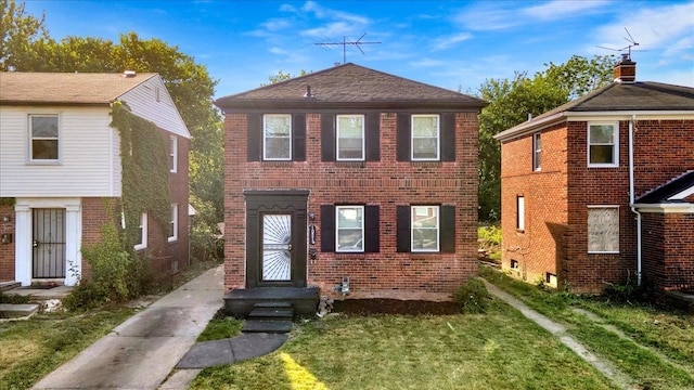 view of front facade with brick siding, a shingled roof, and a front yard