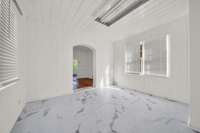 empty room featuring arched walkways and marble finish floor