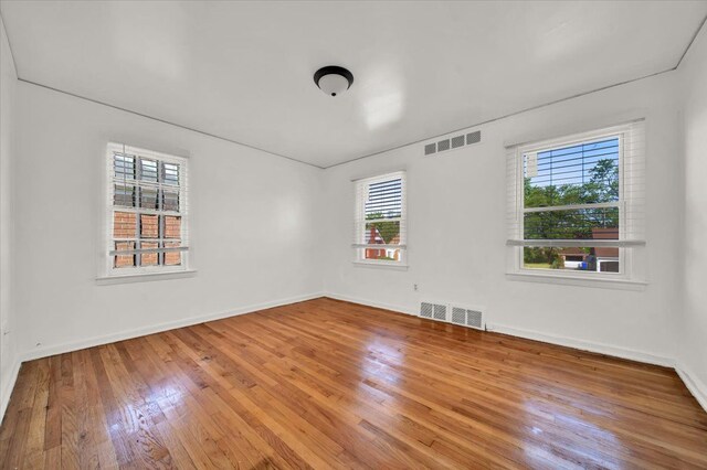 spare room with baseboards, visible vents, and wood-type flooring
