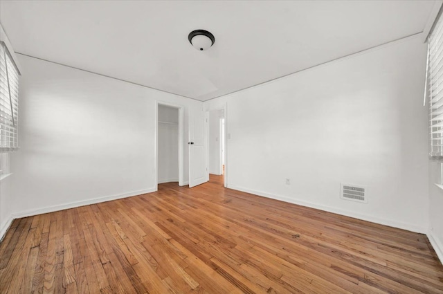empty room with light wood-style flooring, baseboards, and visible vents