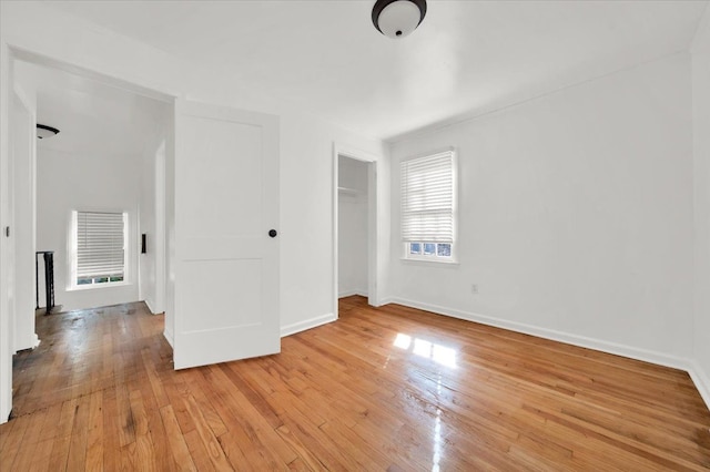 unfurnished bedroom featuring baseboards, light wood-type flooring, and a closet