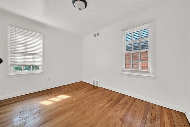 spare room featuring hardwood / wood-style floors, baseboards, and visible vents