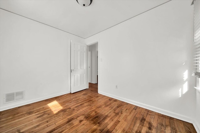 spare room featuring visible vents, baseboards, and hardwood / wood-style flooring