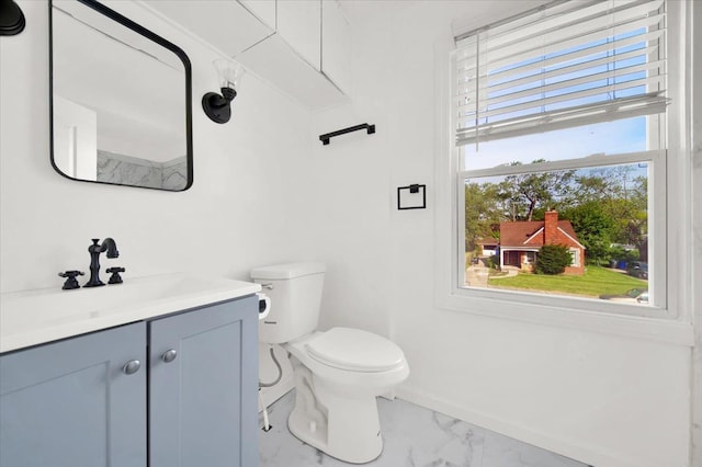 half bath with vanity, toilet, baseboards, and marble finish floor