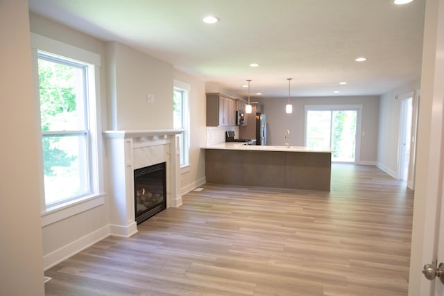 kitchen featuring light wood-type flooring, kitchen peninsula, appliances with stainless steel finishes, and sink