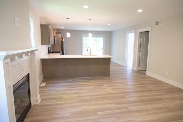 kitchen featuring light hardwood / wood-style floors, pendant lighting, stainless steel appliances, and kitchen peninsula