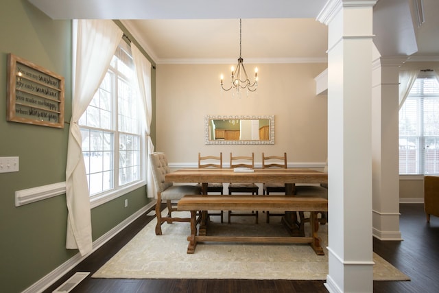 dining space featuring crown molding, decorative columns, dark hardwood / wood-style floors, and an inviting chandelier