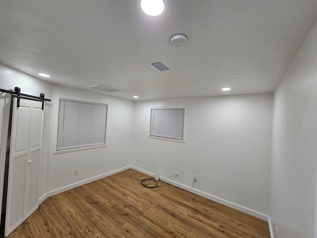 unfurnished room featuring wood-type flooring and a barn door