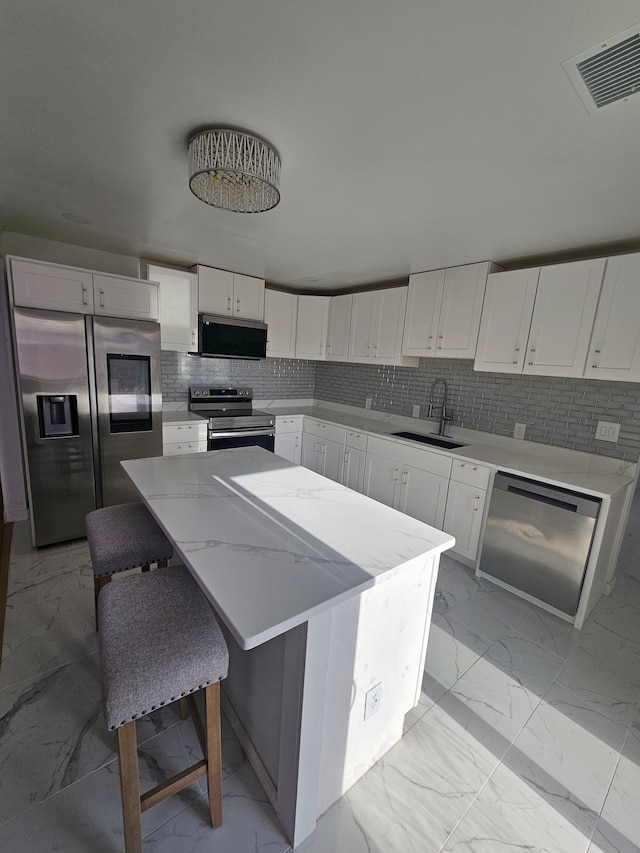 kitchen with white cabinets, sink, stainless steel appliances, and a center island