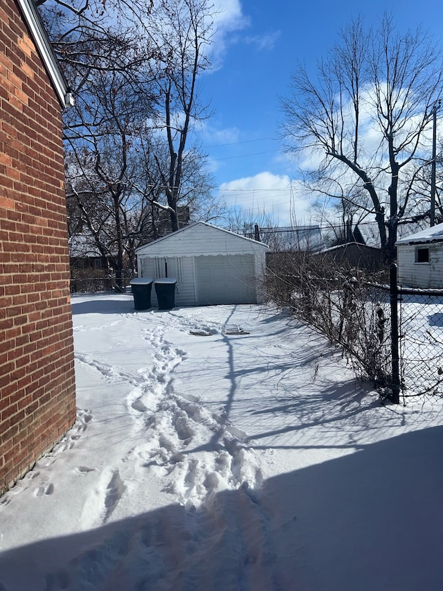 yard layered in snow featuring a garage and an outdoor structure