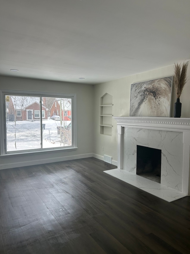 unfurnished living room with dark hardwood / wood-style floors, a high end fireplace, and built in features