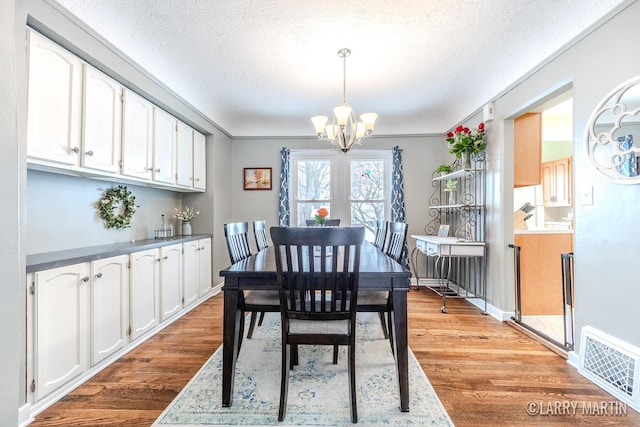 dining area featuring a textured ceiling, hardwood / wood-style flooring, and a chandelier