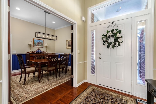 foyer entrance with crown molding, dark wood-style flooring, visible vents, and baseboards