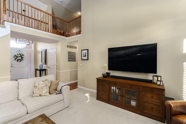 living area featuring carpet floors, baseboards, a towering ceiling, and visible vents