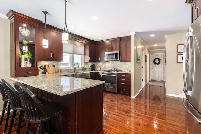 kitchen with a peninsula, appliances with stainless steel finishes, a breakfast bar area, and decorative light fixtures