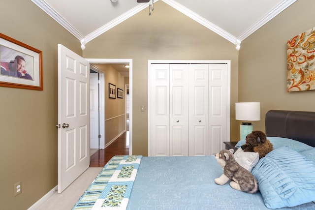 carpeted bedroom with lofted ceiling, a closet, ornamental molding, ceiling fan, and baseboards