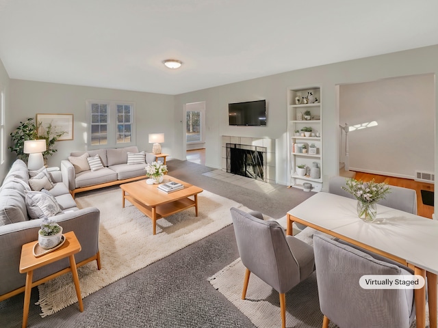 living room featuring carpet, built in shelves, and a fireplace