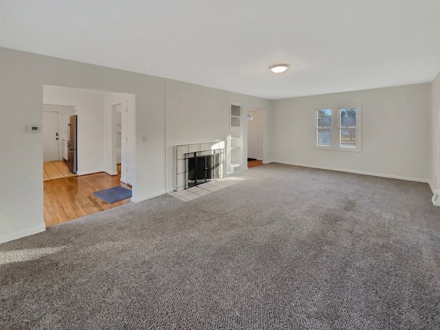 unfurnished living room featuring light colored carpet and a tiled fireplace