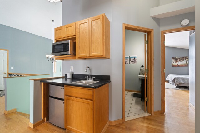 14113 Grandview Dr, Cement City, MI 49233 - kitchen with a sink, stainless steel microwave, light wood-type flooring, dark countertops, and refrigerator