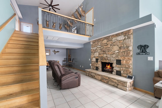 14113 Grandview Dr, Cement City, MI 49233 - living area featuring a high ceiling, tile patterned flooring, a stone fireplace, baseboards, and stairs