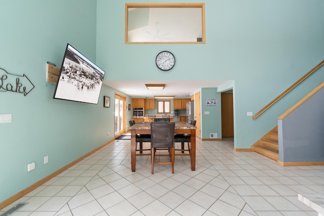 14113 Grandview Dr, Cement City, MI 49233 - dining room featuring stairway, a high ceiling, baseboards, and visible vents