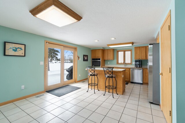 14113 Grandview Dr, Cement City, MI 49233 - kitchen featuring stainless steel appliances, light countertops, a sink, a kitchen island, and a kitchen bar