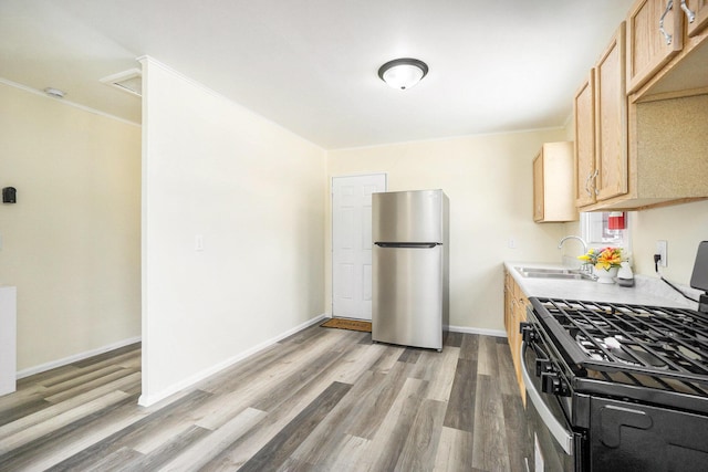 kitchen featuring light hardwood / wood-style flooring, stainless steel refrigerator, light brown cabinets, sink, and black range with gas cooktop