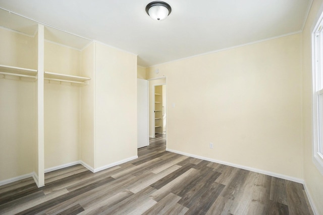 unfurnished bedroom featuring ornamental molding, dark wood-type flooring, and a closet