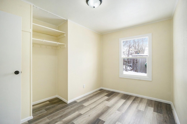 unfurnished bedroom with a closet, hardwood / wood-style floors, and crown molding