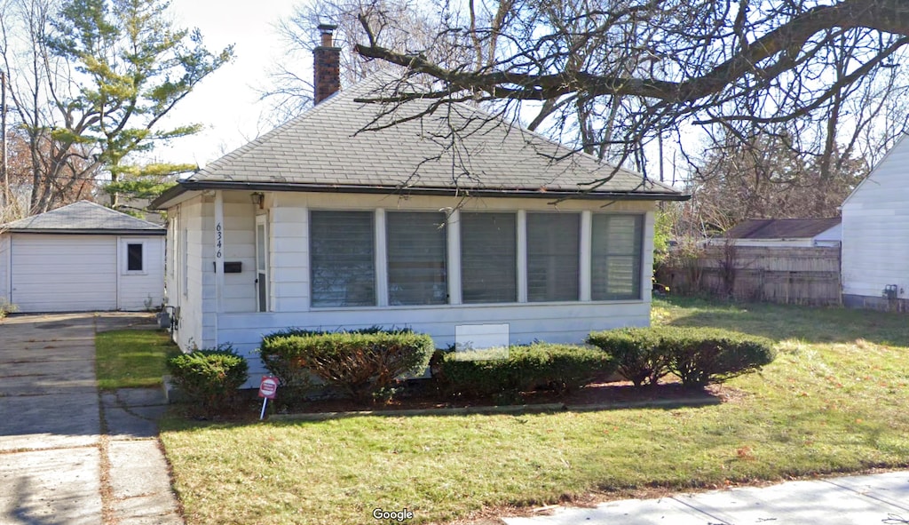 bungalow featuring an outbuilding, a chimney, a front yard, and fence