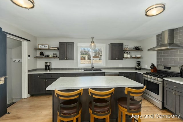 kitchen featuring a center island, appliances with stainless steel finishes, wall chimney exhaust hood, and a barn door