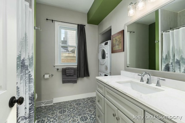 bathroom with stacked washer and dryer, tile patterned flooring, and vanity