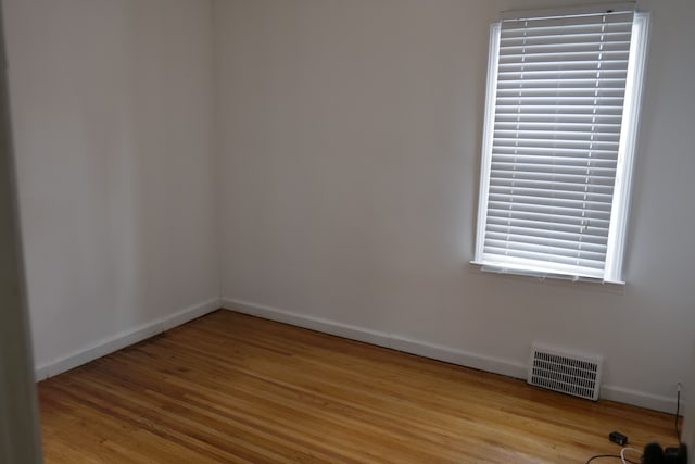 empty room with light wood-style flooring, visible vents, and baseboards