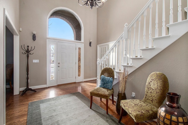 entrance foyer featuring a high ceiling, baseboards, a chandelier, and wood finished floors