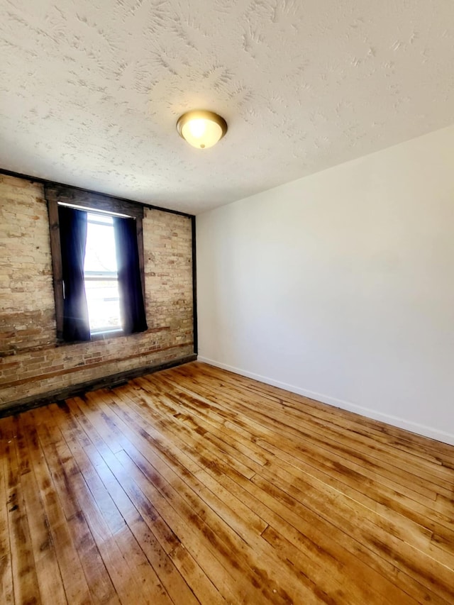 unfurnished room featuring a textured ceiling, baseboards, and hardwood / wood-style flooring