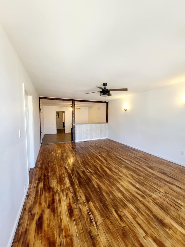 unfurnished living room featuring wood-type flooring, baseboards, and ceiling fan