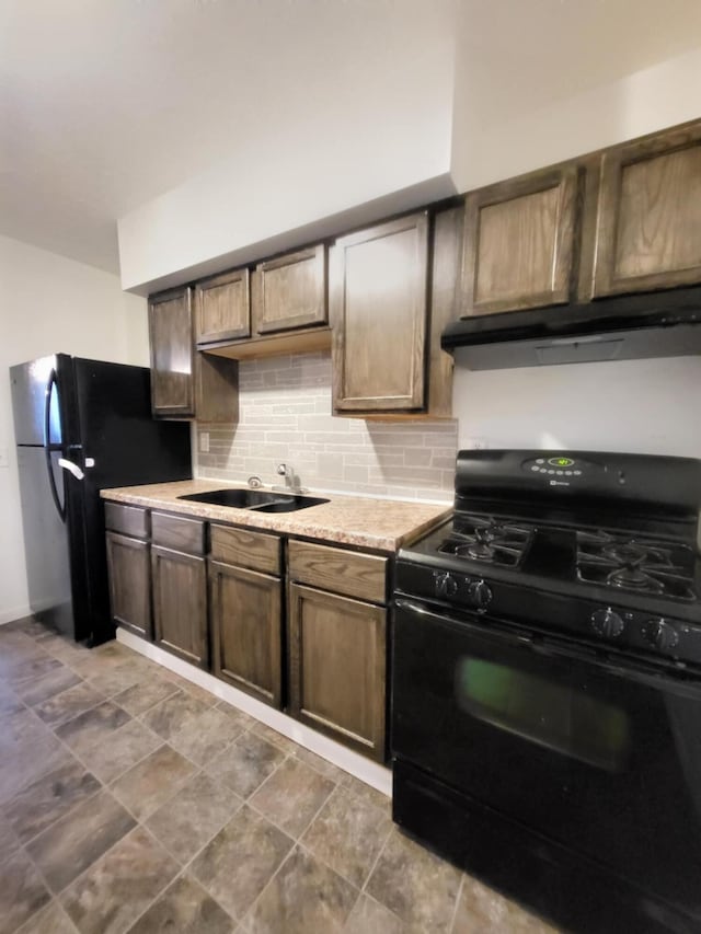 kitchen with light countertops, under cabinet range hood, a sink, backsplash, and black appliances