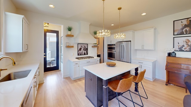 kitchen featuring sink, stainless steel appliances, white cabinetry, and a center island